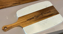 White marble cutting board with wooden handle and 'Home Sweet Home' engraving on a light gray surface.